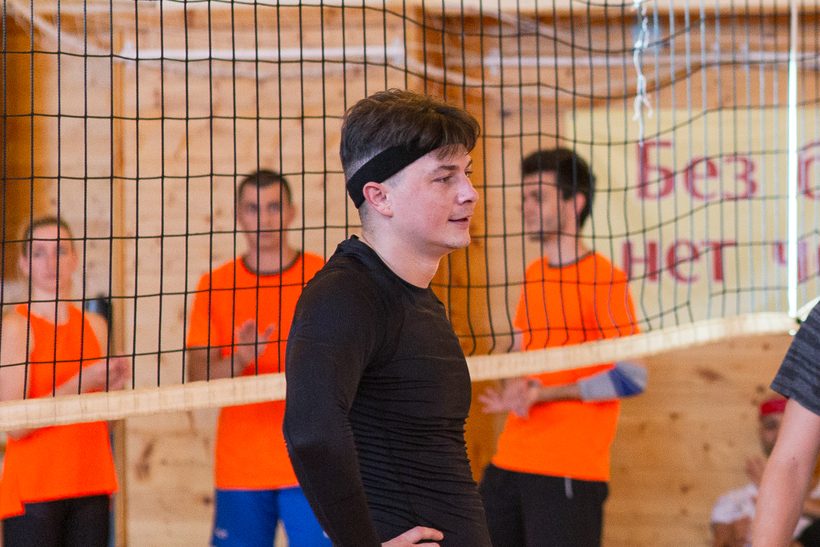 Группа взрослых на разминке перед тренировкой по волейболу